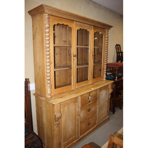 744 - A stripped pine bookcase, the upper section enclosed three shaped panel glazed doors over three cent... 