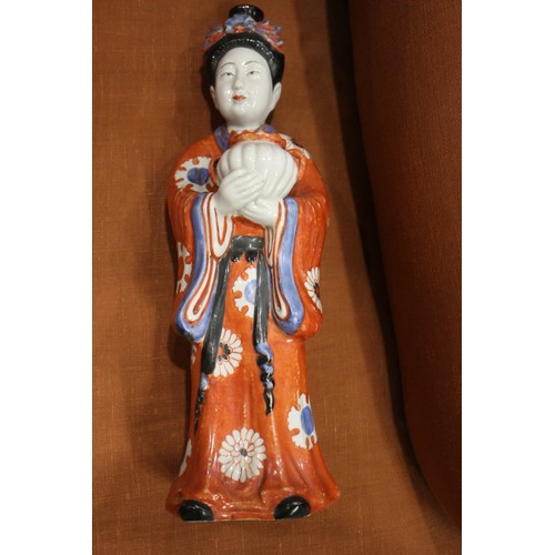 89 - A pair of Chinese porcelain figures of women in orange robes holding jars, 14