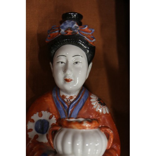 89 - A pair of Chinese porcelain figures of women in orange robes holding jars, 14