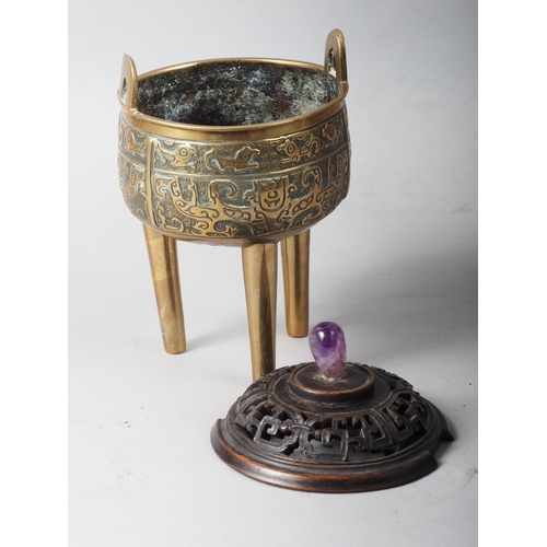 107 - A Chinese brass censor with engraved decorated and carved wooden top and amethyst knop, on three tap... 