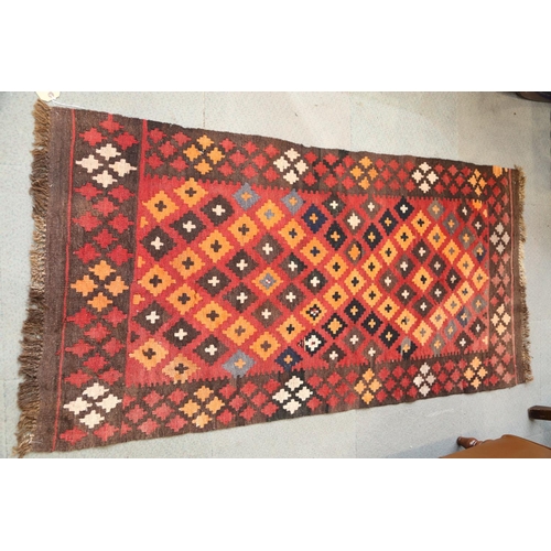 543 - A kelim rug with all-over stepped medaillions on a red ground, 33