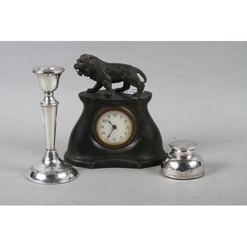 139 - A pewter cased mantel clock with a lion surmount, a silver inkwell and a filled silver candlestick