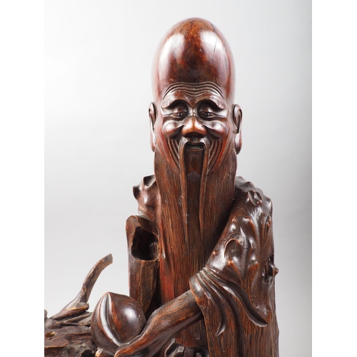 103 - A Chinese carved fruitwood figure of a Laotsu, on root stand, 26 1/2