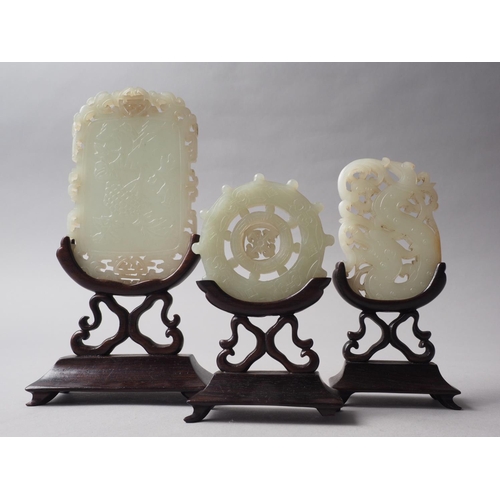 112 - Three carved jade panels, on hardwood stands, largest 6