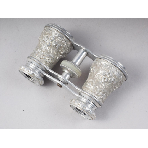 122 - A pair of embossed and chased aluminium cased opera glasses by Sharman D Neill Belfast, inscribed SS... 