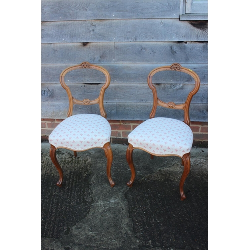 423 - A pair of Victorian carved walnut loop back side chairs, on cabriole supports