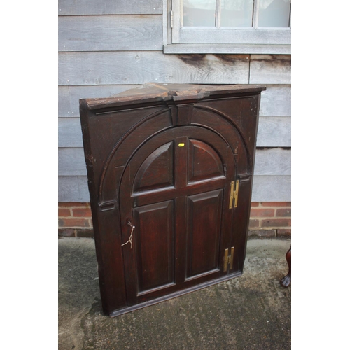 434 - An 18th century oak corner hanging cupboard, fitted shaped shelves enclosed arch top panel door, 33