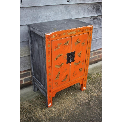 466 - A Chinese red lacquered butterfly decorated cupboard, on stile supports, 22