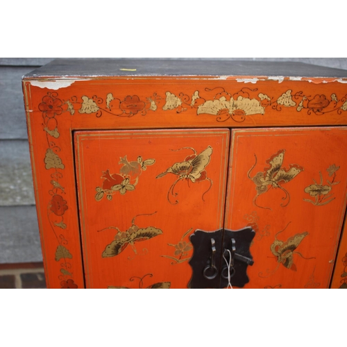 466 - A Chinese red lacquered butterfly decorated cupboard, on stile supports, 22