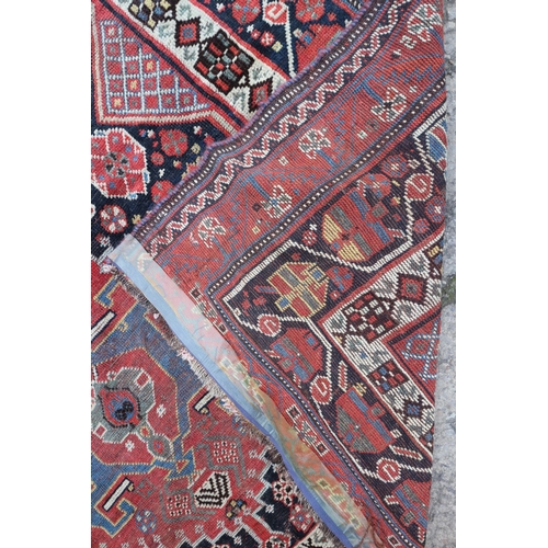 630 - A Qashqai rug with three hooked guls on a black ground and multi-bordered in rust, blue, yellow and ... 