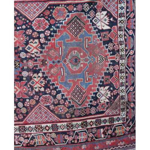 630 - A Qashqai rug with three hooked guls on a black ground and multi-bordered in rust, blue, yellow and ... 