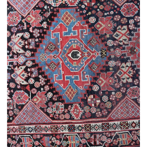 630 - A Qashqai rug with three hooked guls on a black ground and multi-bordered in rust, blue, yellow and ... 