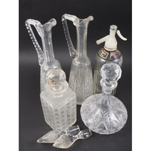 66 - A pair of cut glass claret jugs, a spirit decanter, a bulbous decanter and a Schweppes soda siphon