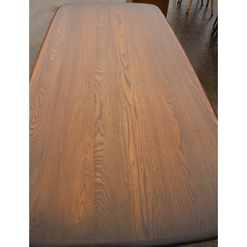 628 - An Ercol elm shape top dining table, on panel end stretchered supports, 72