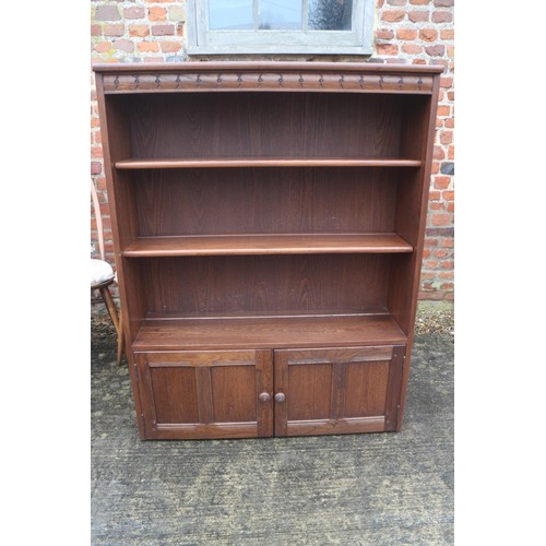 633 - An Ercol elm bookcase, fitted two doors, on block base, 38