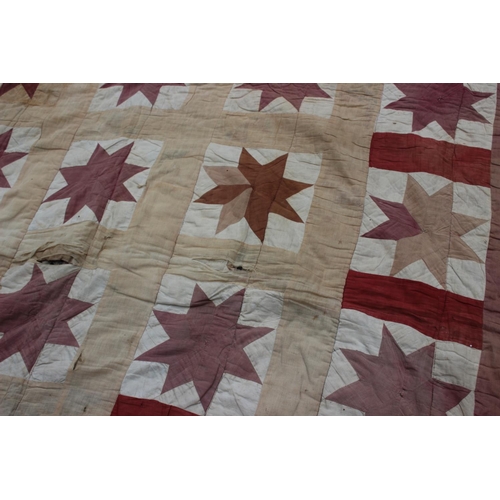 193 - An early 20th century quilt with thirty central star-shaped guls in shades of red and cream, 74 1/2