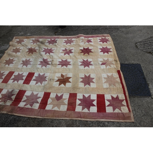 193 - An early 20th century quilt with thirty central star-shaped guls in shades of red and cream, 74 1/2