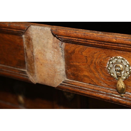 522 - An early 18th century oak chest of three long drawers with fielded panel fronts and brass drop handl... 