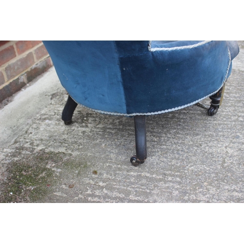 523 - A late 19th century low seat occasional chair, button upholstered in a blue velvet, on turned and ca... 