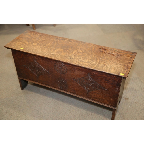 547 - An early 18th century oak coffer with chip carved front and hinged lid, on panel end supports, 39