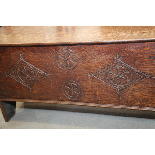 547 - An early 18th century oak coffer with chip carved front and hinged lid, on panel end supports, 39