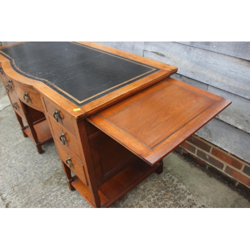 654 - An Arts & Crafts walnut break bowfront double pedestal desk with tooled lined top, fitted seven draw... 