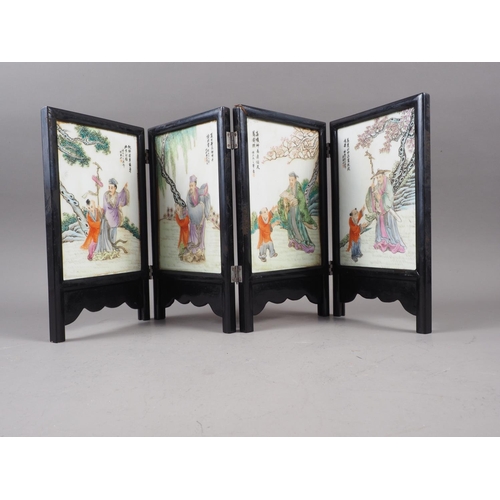 90 - A Chinese four-section folding screen, decorated figures in landscapes, 10 1/4