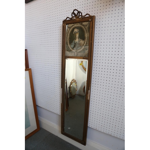 567 - An oval gilt metal framed wall mirror with floral decoration and ribbon finial, 17 3/4