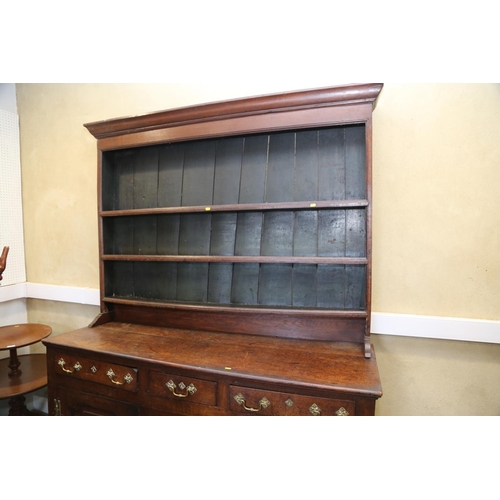 566 - A George III oak dresser, fitted shelves over three drawers and two cupboards enclosed arched panel ... 