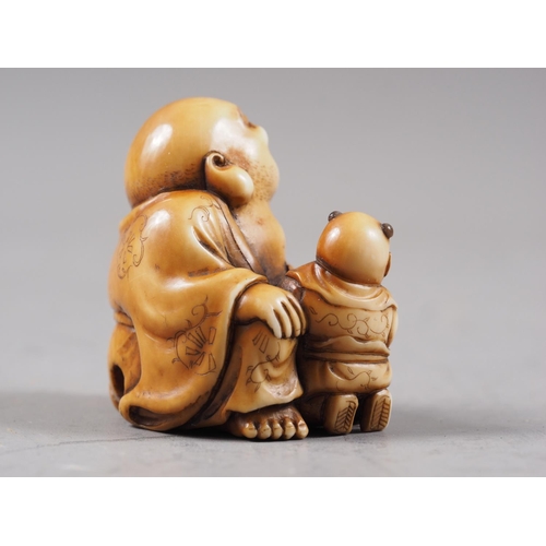 162 - A Japanese carved ivory netsuke Hotei with acolyte painting on his stomach, signed, 1 1/4