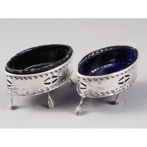 370 - A pair of Georgian silver oval salts with pierced and engraved decoration and blue glass liners