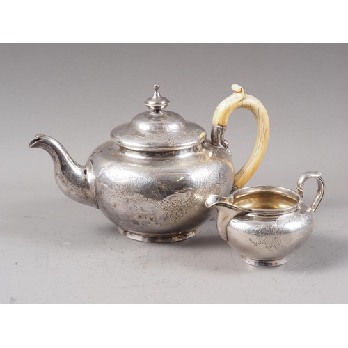 394 - A Victorian silver teapot with engraved scrolled and coat of arms decoration and a matching milk jug... 