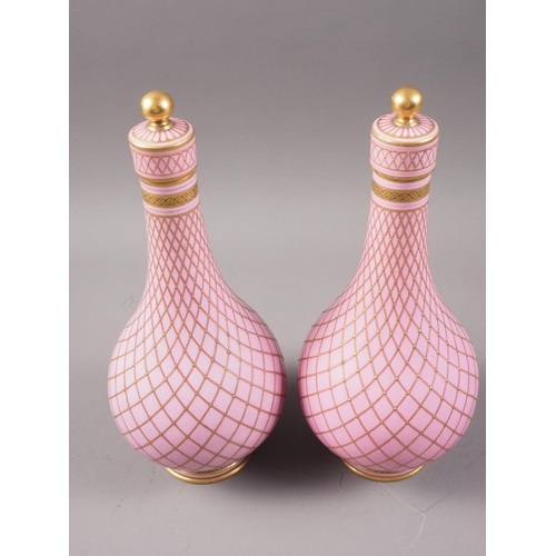 41 - A pair of Sevres style porcelain bottle vases and covers with all-over lattice decoration on a pink ... 