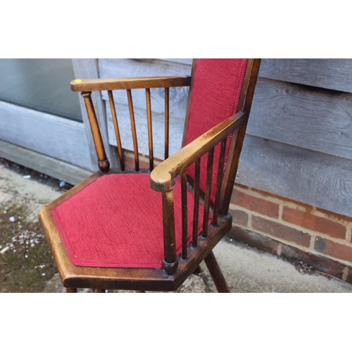 701 - A polished as walnut spindle back elbow chair, upholstered in a red fabric, on turned supports