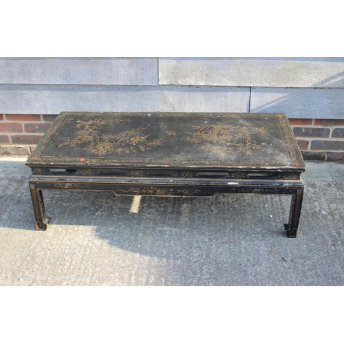 673 - A Chinese black and gold lacquered low occasional table, on scroll end supports, 49