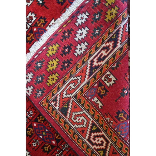 729 - A Caucasian rug with shaped guls, on a red ground and multi-geometric borders, 75