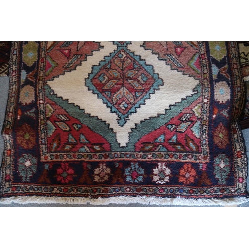 738 - A Kazak style rug with nine star diamond lozenges on a cream ground with pink edges and blue floral ... 