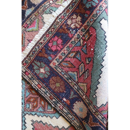 738 - A Kazak style rug with nine star diamond lozenges on a cream ground with pink edges and blue floral ... 