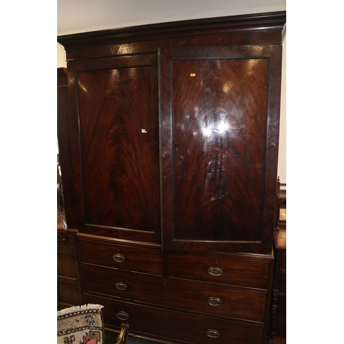 544 - An early 19th century figured mahogany linen press, the upper section fitted trays enclosed two pane... 