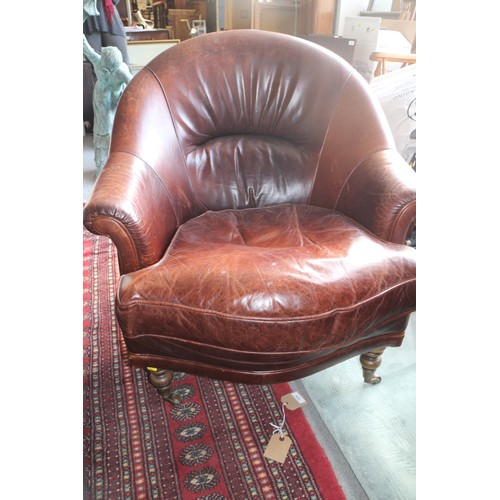 676 - A pair of Art Deco design dark tan leather tub-shape armchairs with loose seat cushions, on turned a... 