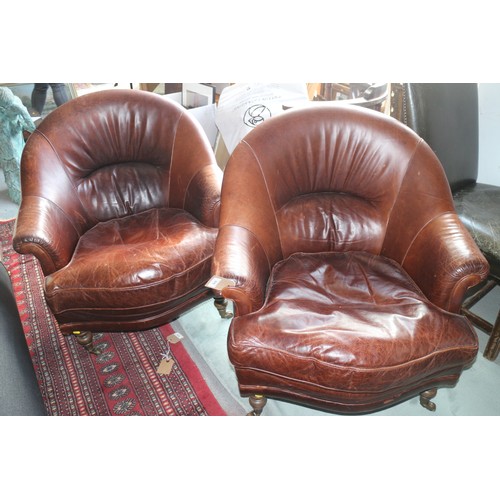 676 - A pair of Art Deco design dark tan leather tub-shape armchairs with loose seat cushions, on turned a... 