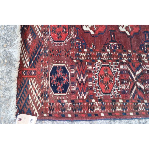 728 - An antique Bokhara carpet of traditional design with forty-eight octagonal guls on a plum ground, 10... 