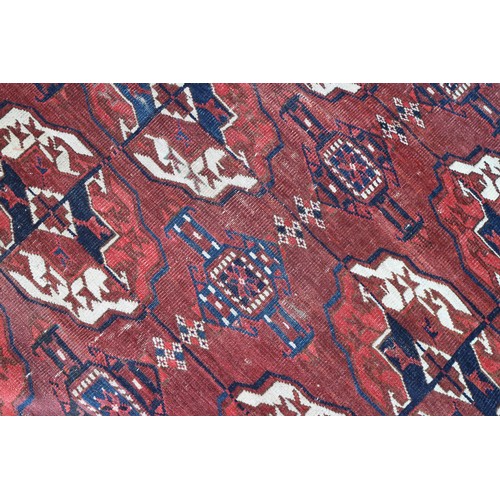 728 - An antique Bokhara carpet of traditional design with forty-eight octagonal guls on a plum ground, 10... 