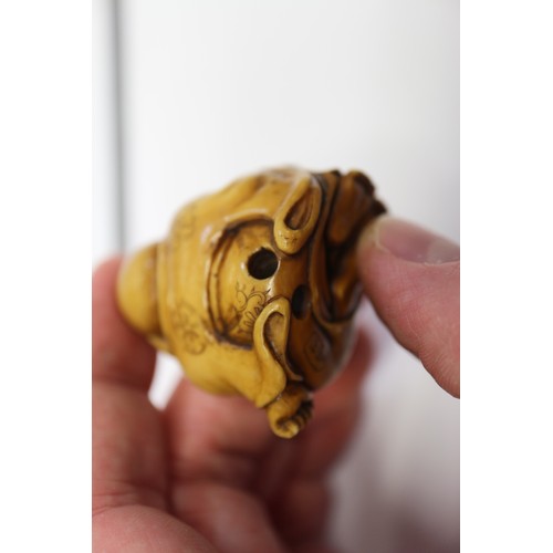 162 - A Japanese carved ivory netsuke Hotei with acolyte painting on his stomach, signed, 1 1/4