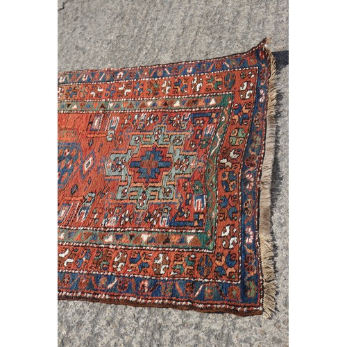 735 - A Kazak tribal runner with eight various guls/medallions on a cherry/rust ground and triple borders ... 