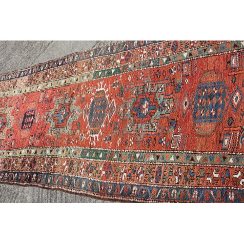 735 - A Kazak tribal runner with eight various guls/medallions on a cherry/rust ground and triple borders ... 