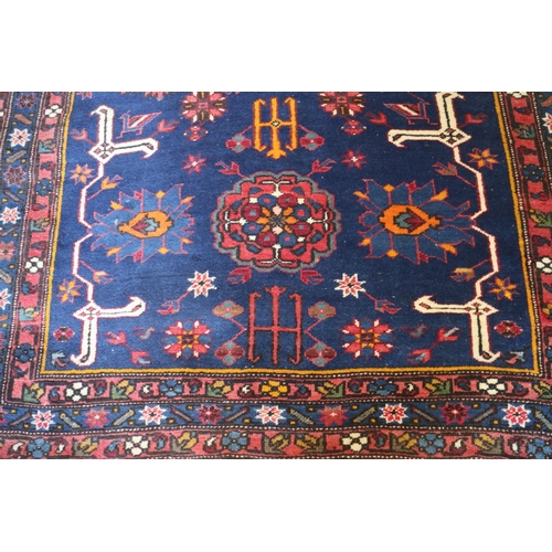 631 - A Kuba rug with three medallions, candelabra and stylised birds on a dark blue ground and triple-bor... 