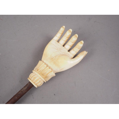 131 - A 19th century carved ivory hand back-scratcher with palm wood stem, 17 1/2