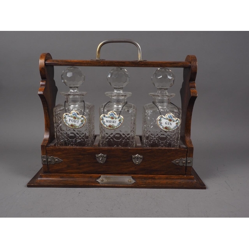 186 - An oak three-decanter Tantalus