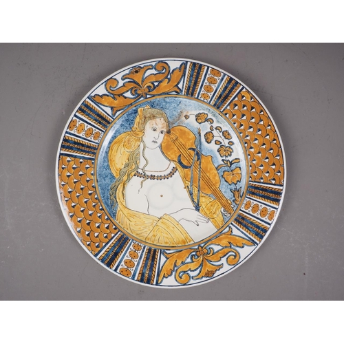 36 - An Italian plate, decorated with a nude woman playing the violin (chip to rim)